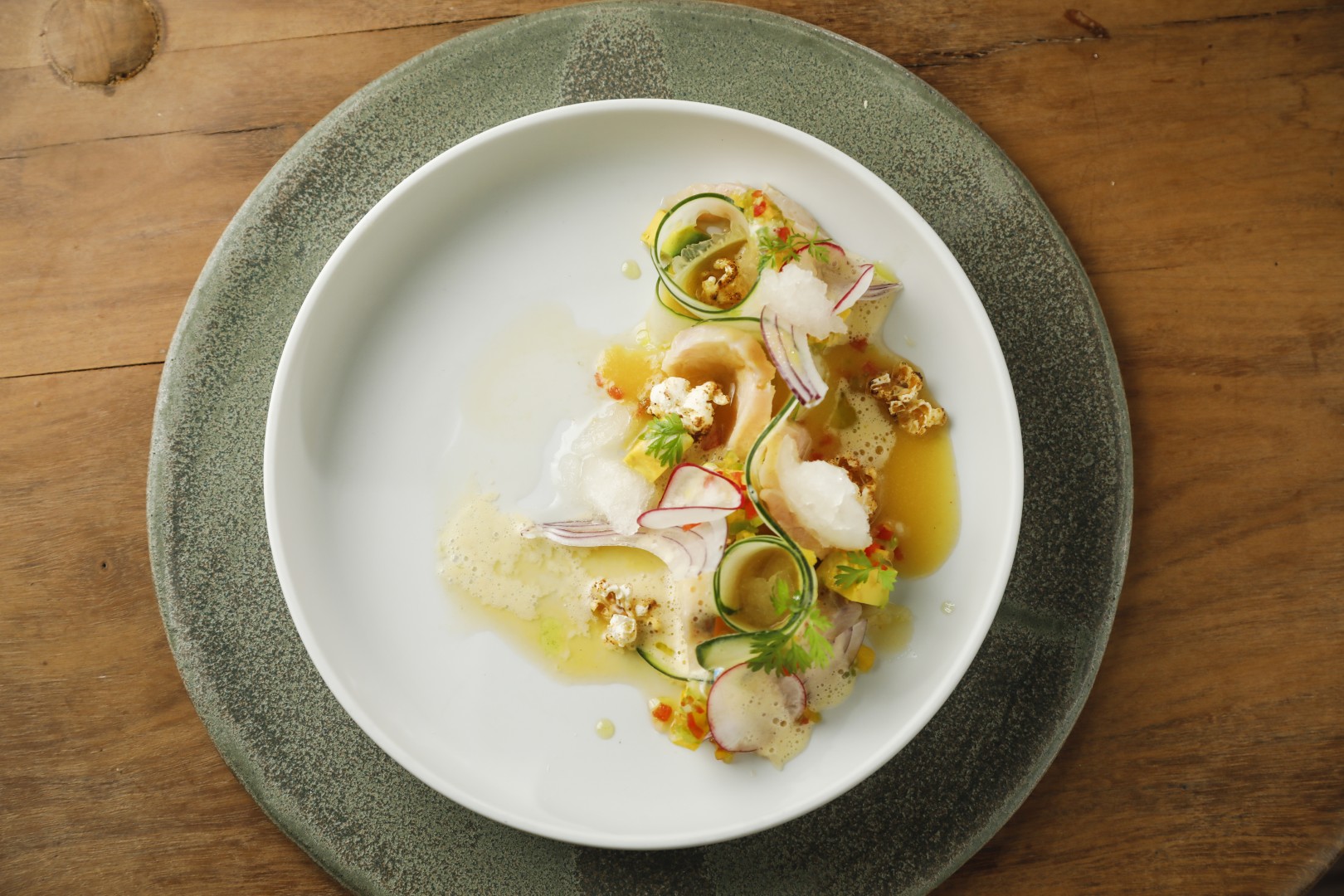 Artfully plated gourmet dish with delicate seafood, vegetables, and sauce arranged on a white plate.