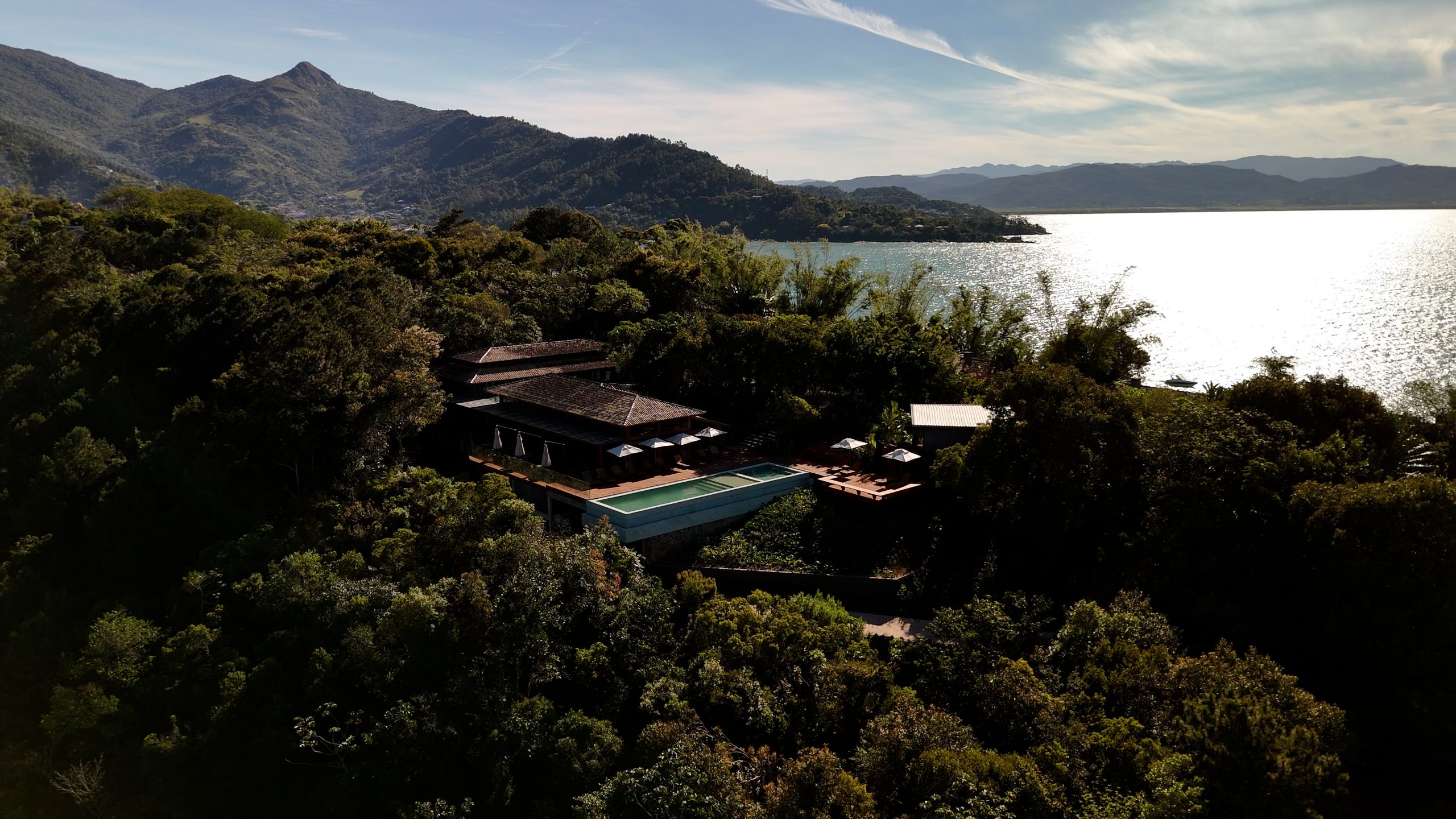 Secluded luxury retreat with infinity pool overlooking forest, mountains, and sea.