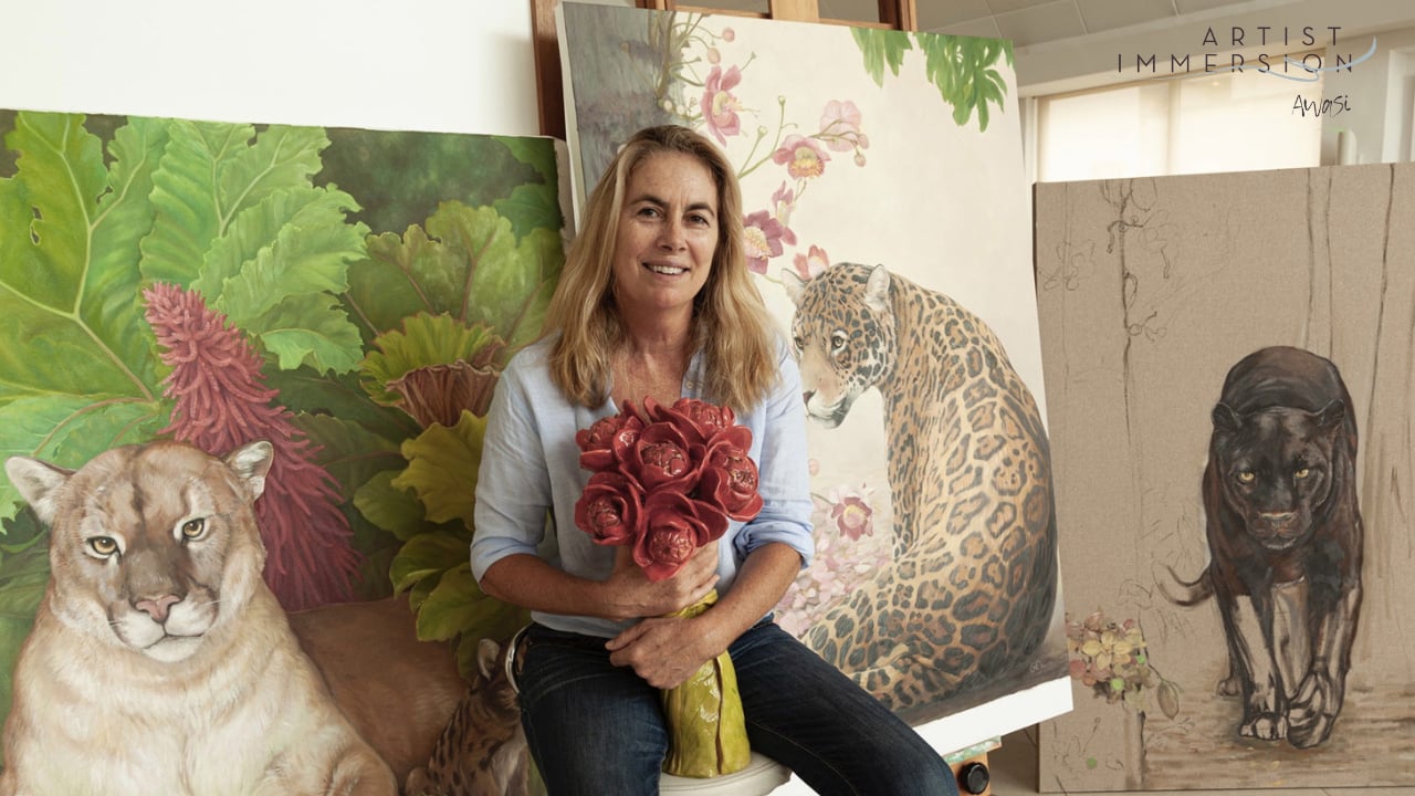 Woman holding red flowers in an art studio surrounded by animal paintings.