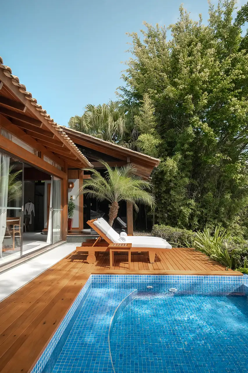 Deck with two lounge chairs beside a small blue‑tiled pool in a tropical setting.