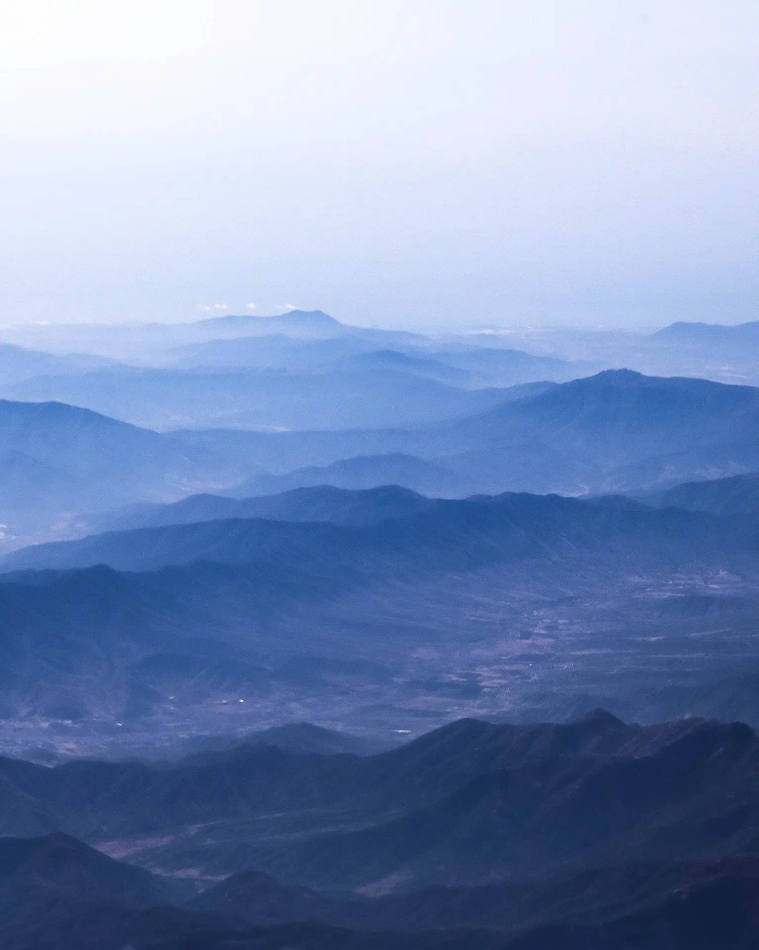 Layered mountain ranges fading into the distance under a clear sky.