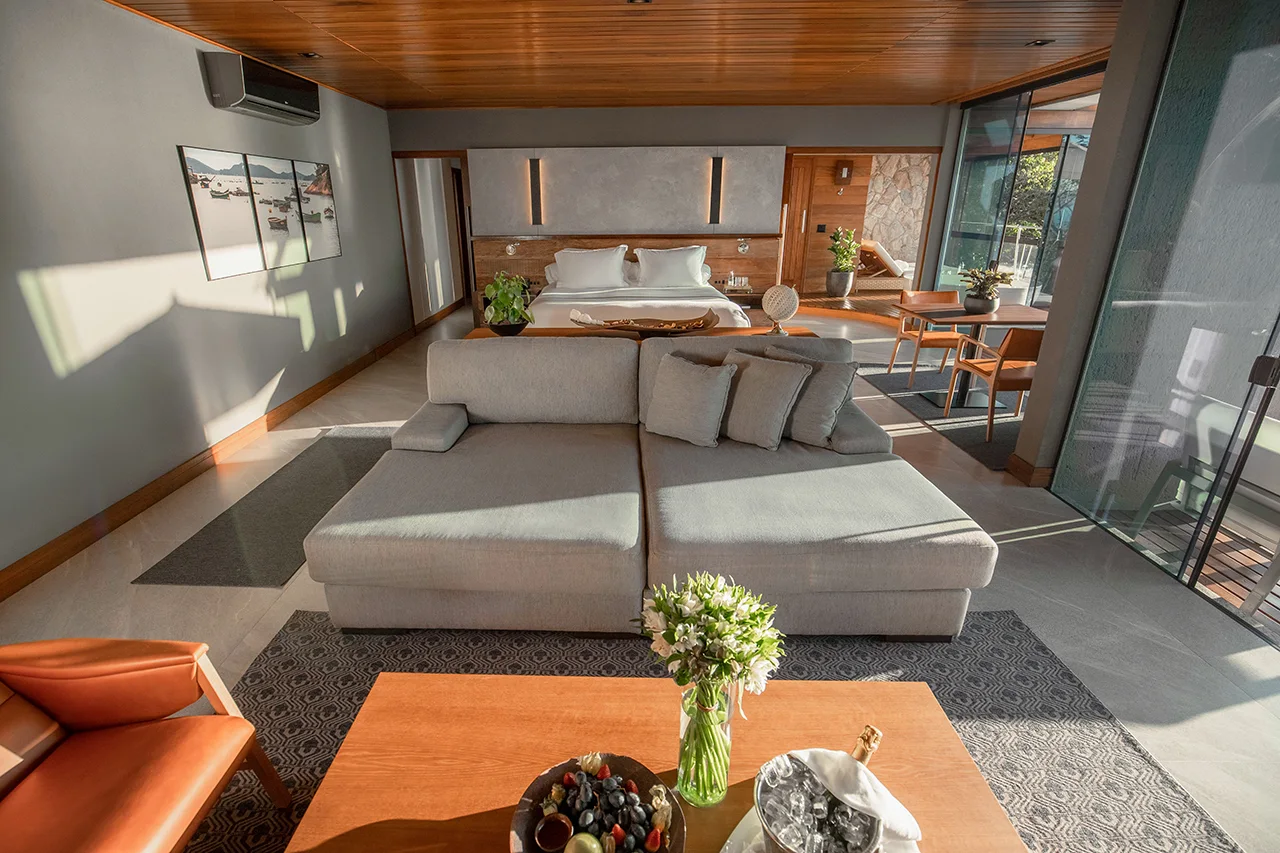 Bright, elegant suite with sofa, fresh flowers, and a sunlit bedroom opening to a private terrace.