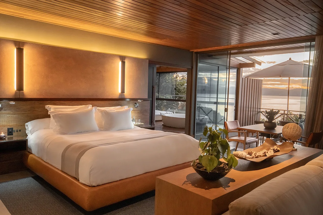 Warm, modern suite with terrace, sunset views over the water, and an outdoor soaking tub.