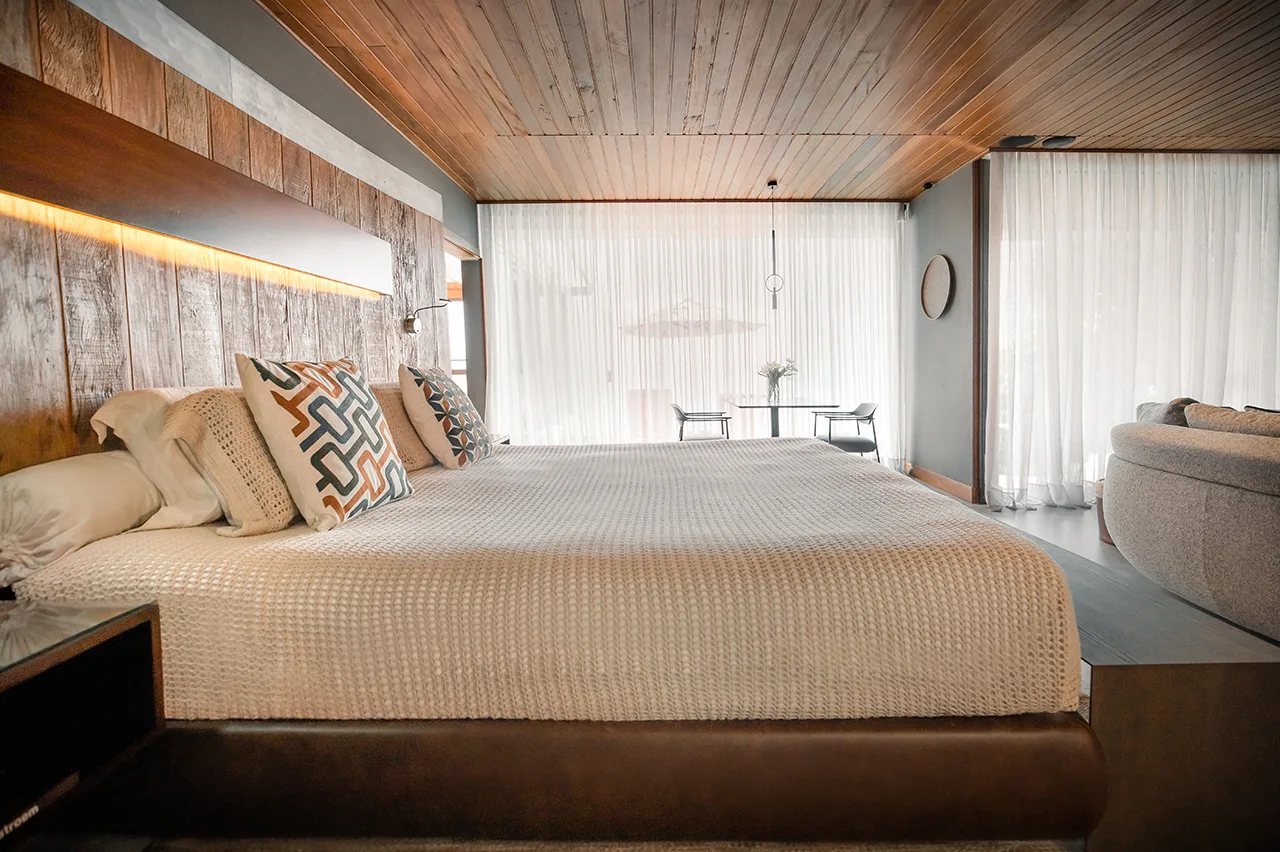 Modern bedroom with large bed, warm wood details, and soft natural light