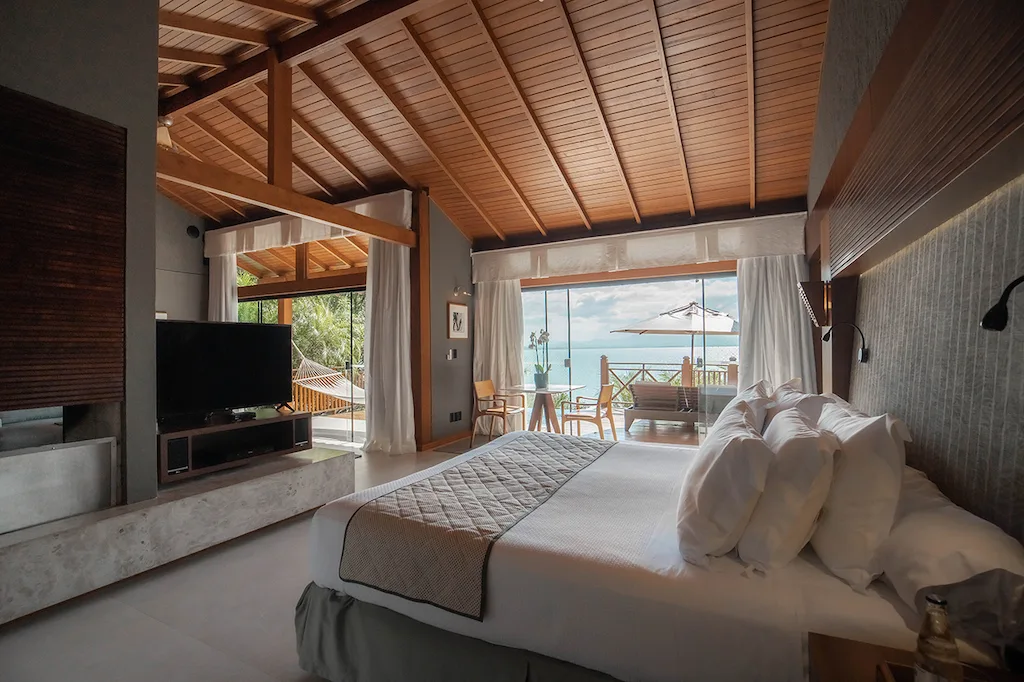Cozy bedroom with wooden ceiling, ocean view, and private terrace