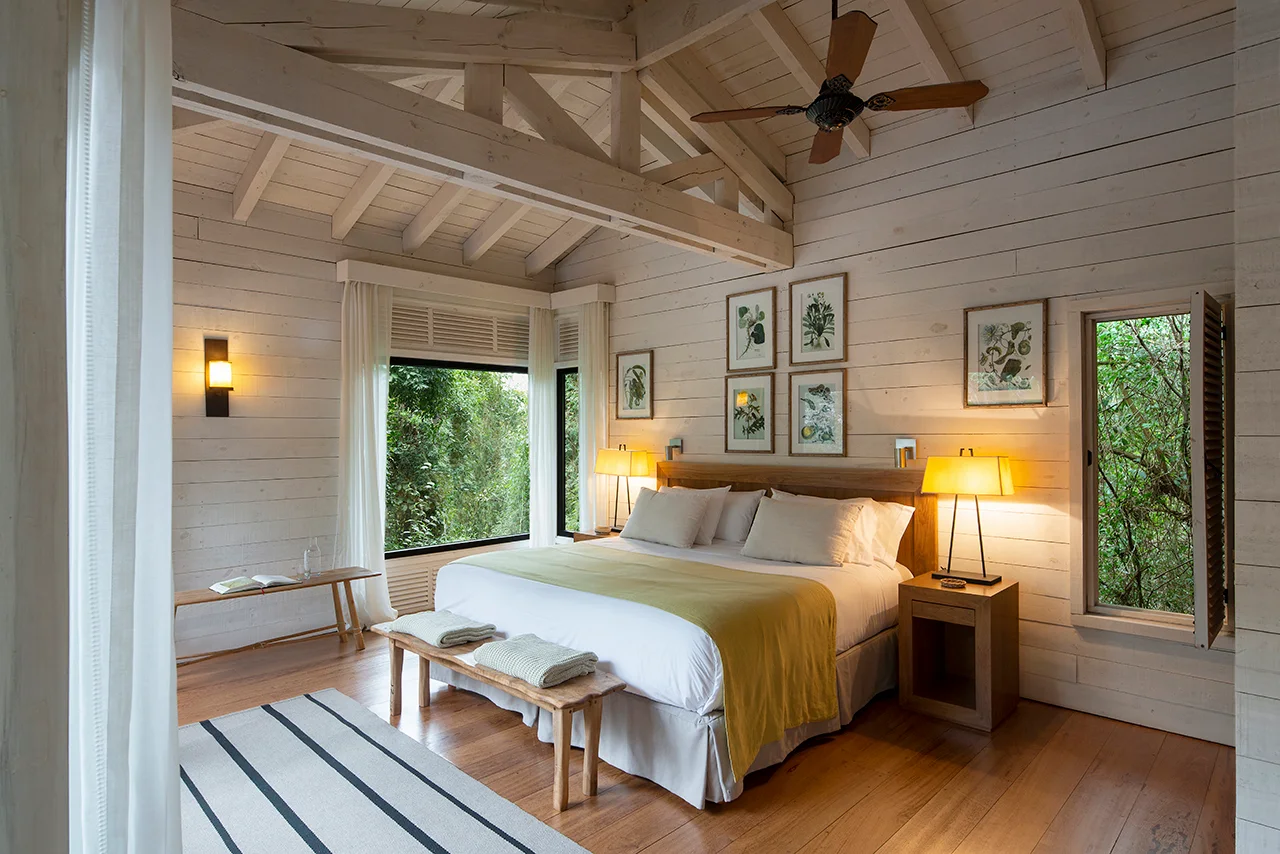 Bright cozy bedroom with wooden beams, large windows, and soft natural decor