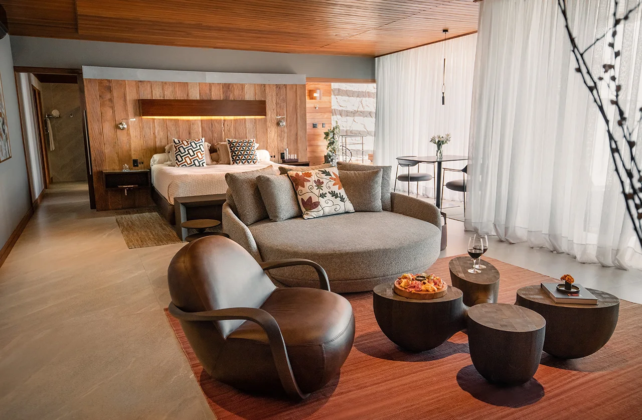 Spacious modern suite with bed, lounge area, and warm wooden design