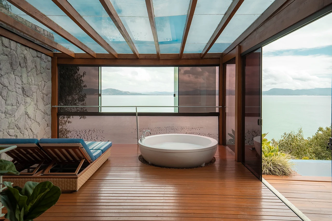 Outdoor terrace with freestanding bathtub, lounge chairs, and panoramic ocean views