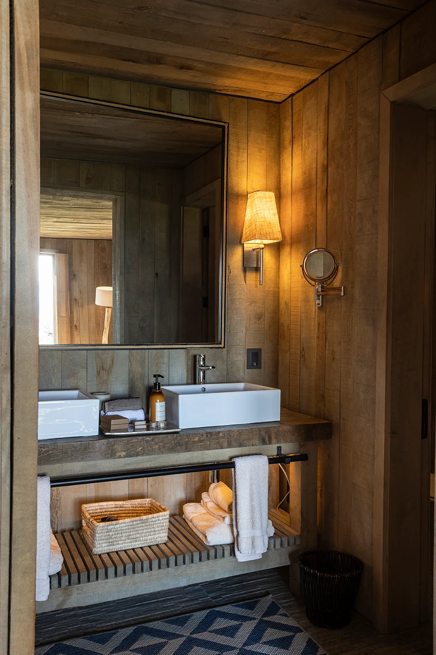 Warm wooden bathroom with double sinks, soft lighting, and natural, cozy decor