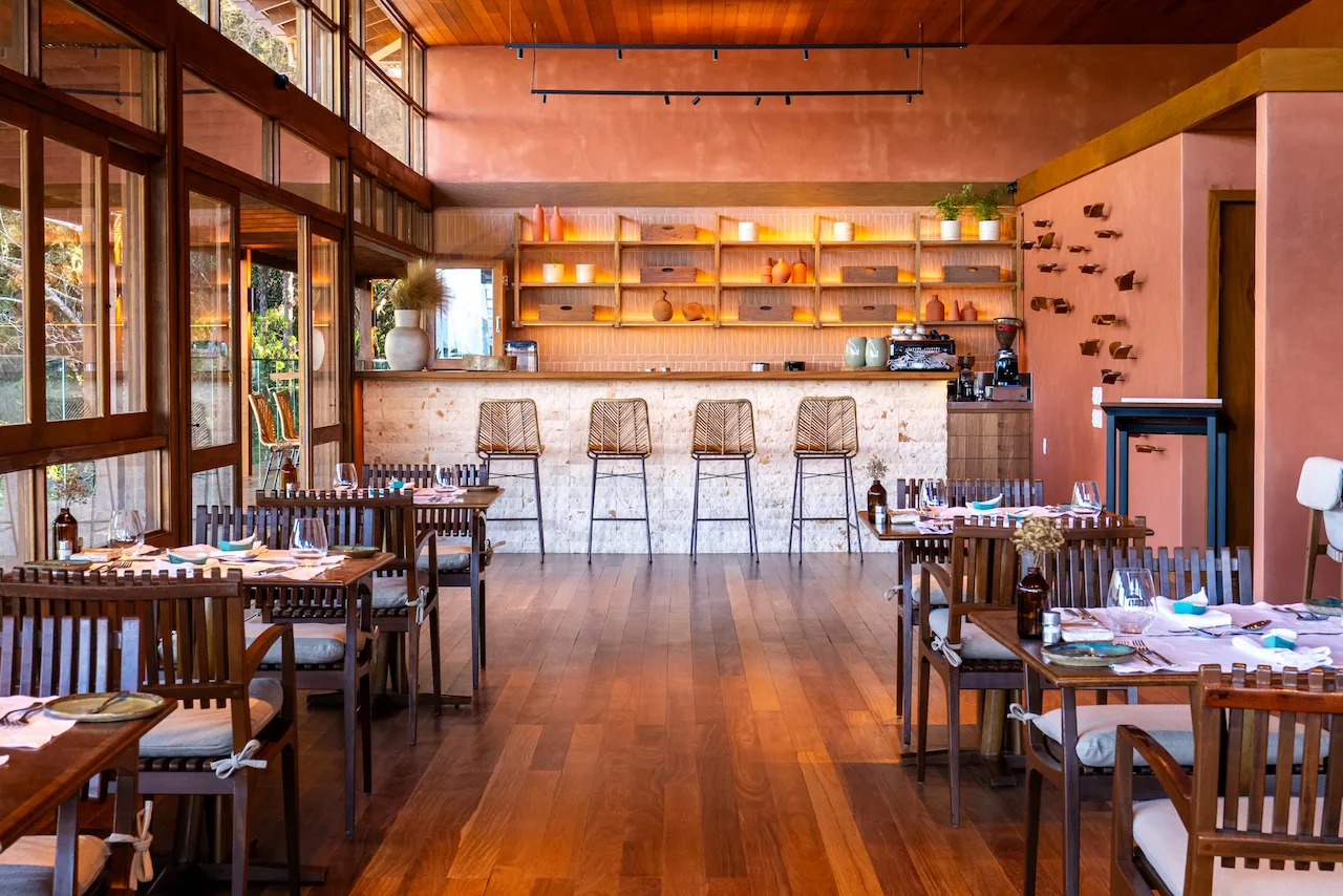 Warm, modern restaurant interior with wooden tables, bar seating, and soft ambient lighting