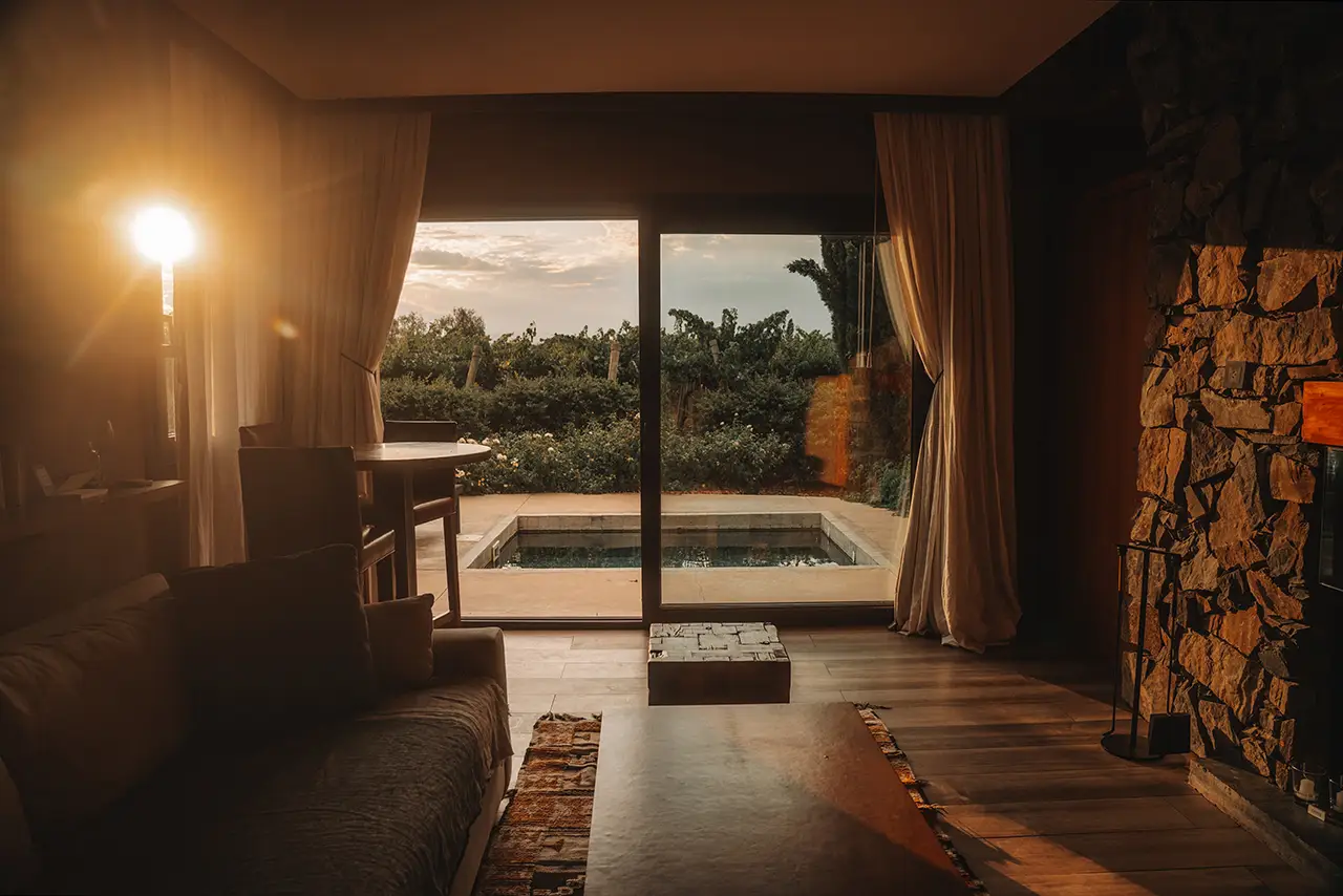 Warm, cozy living room with sunset light, fireplace, and a view of a private outdoor plunge pool