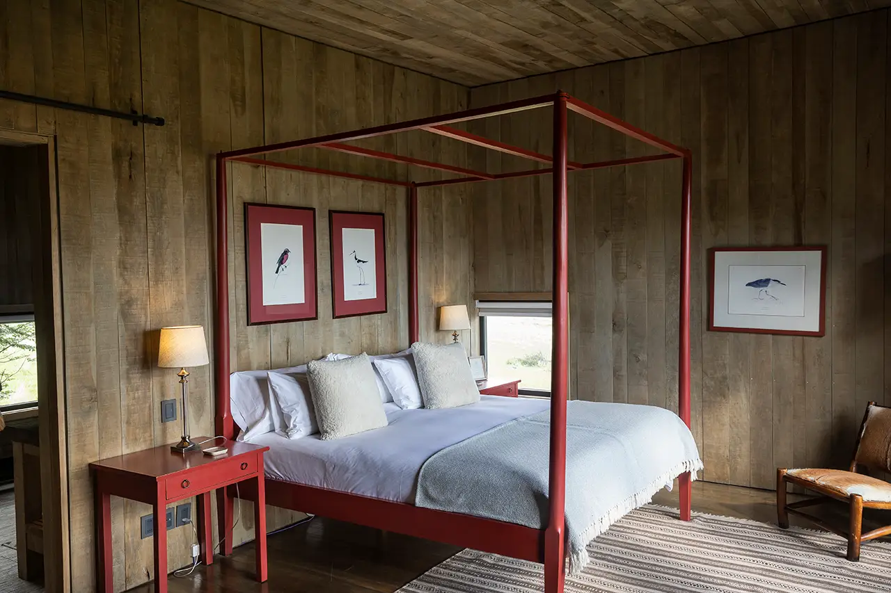 Cozy bedroom with a red canopy bed, wooden walls, and soft neutral decor