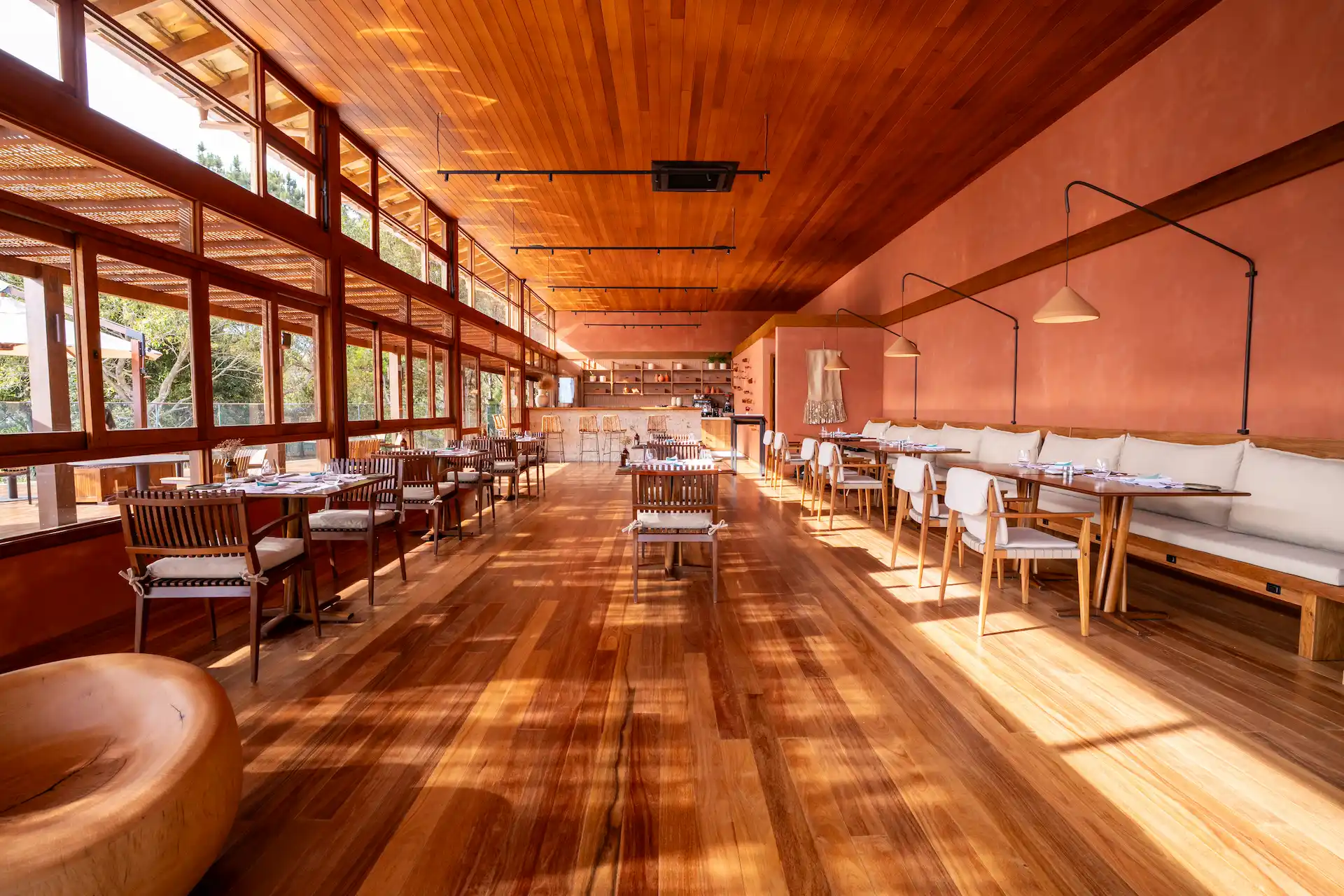 Spacious restaurant interior with wooden floors large windows and warm natural light creating an inviting dining atmosphere