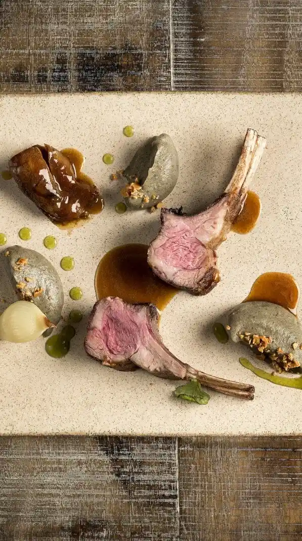 Gourmet lamb chops plated with sauce puree and vegetables in an elegant fine dining presentation