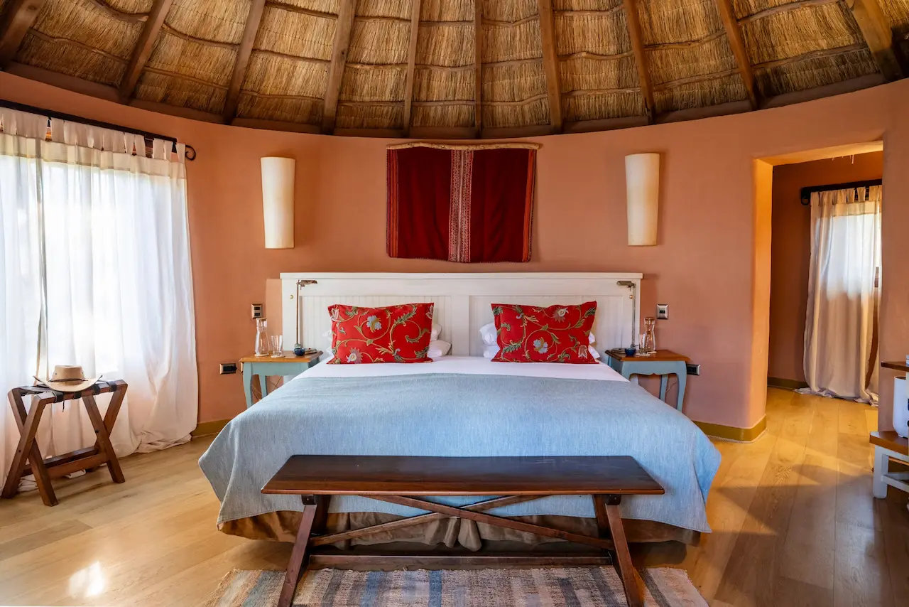 Cozy bedroom with thatched roof king bed colorful cushions and warm natural light creating a relaxing atmosphere