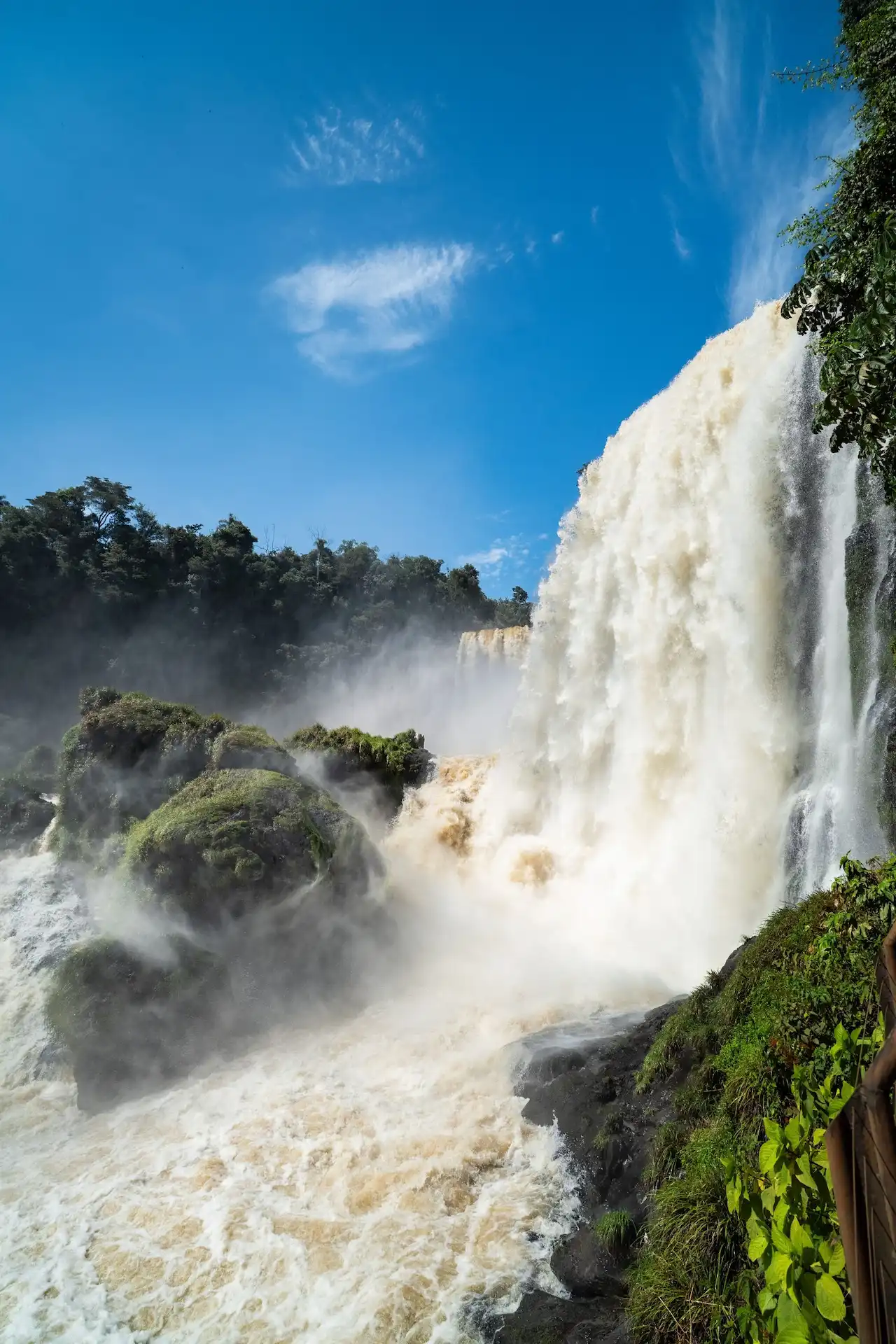 Iguazú falls cascading through lush subtropical rainforest under blue sky