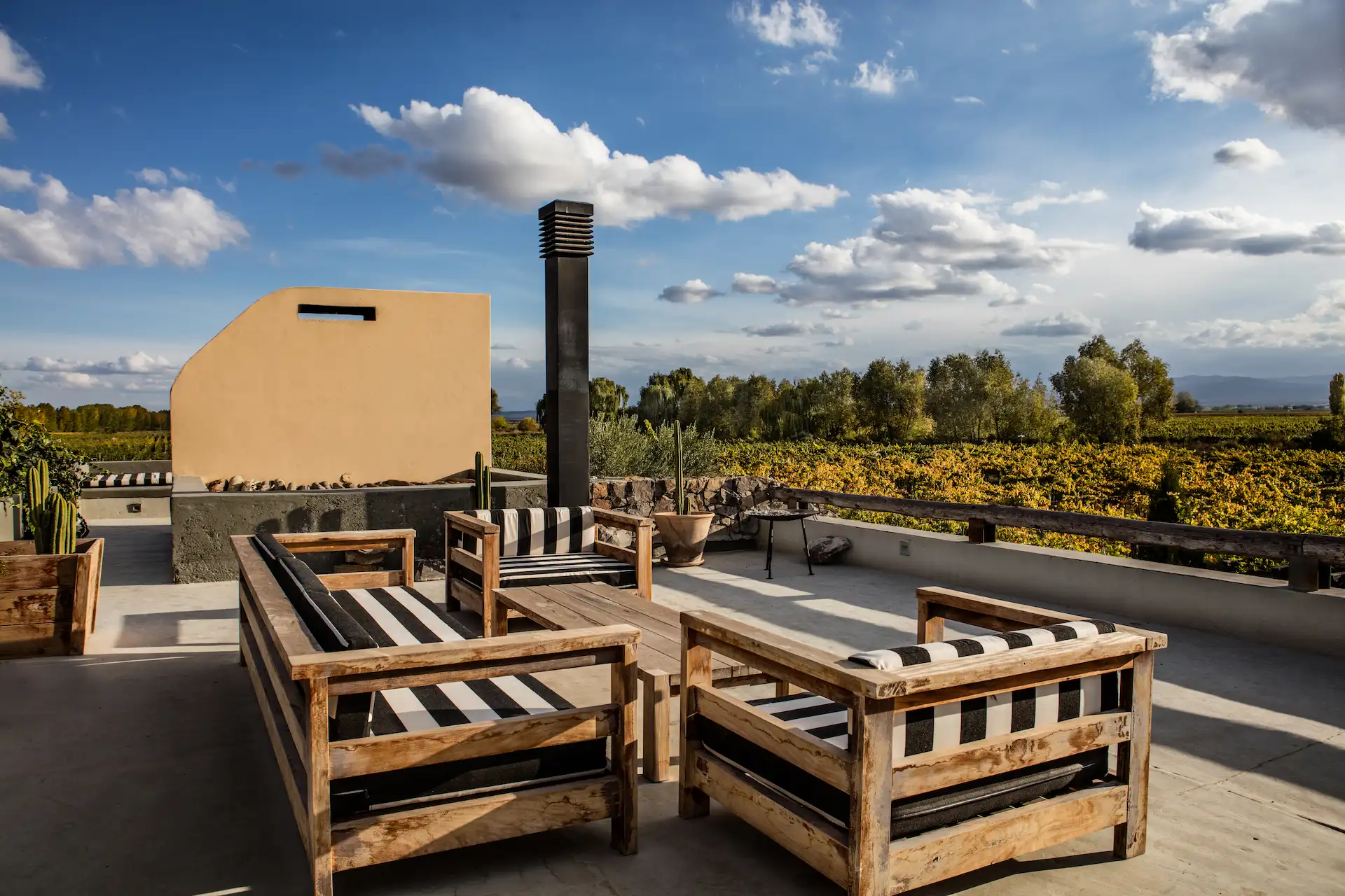 Outdoor terrace with wooden seating overlooking vineyards and countryside under a bright