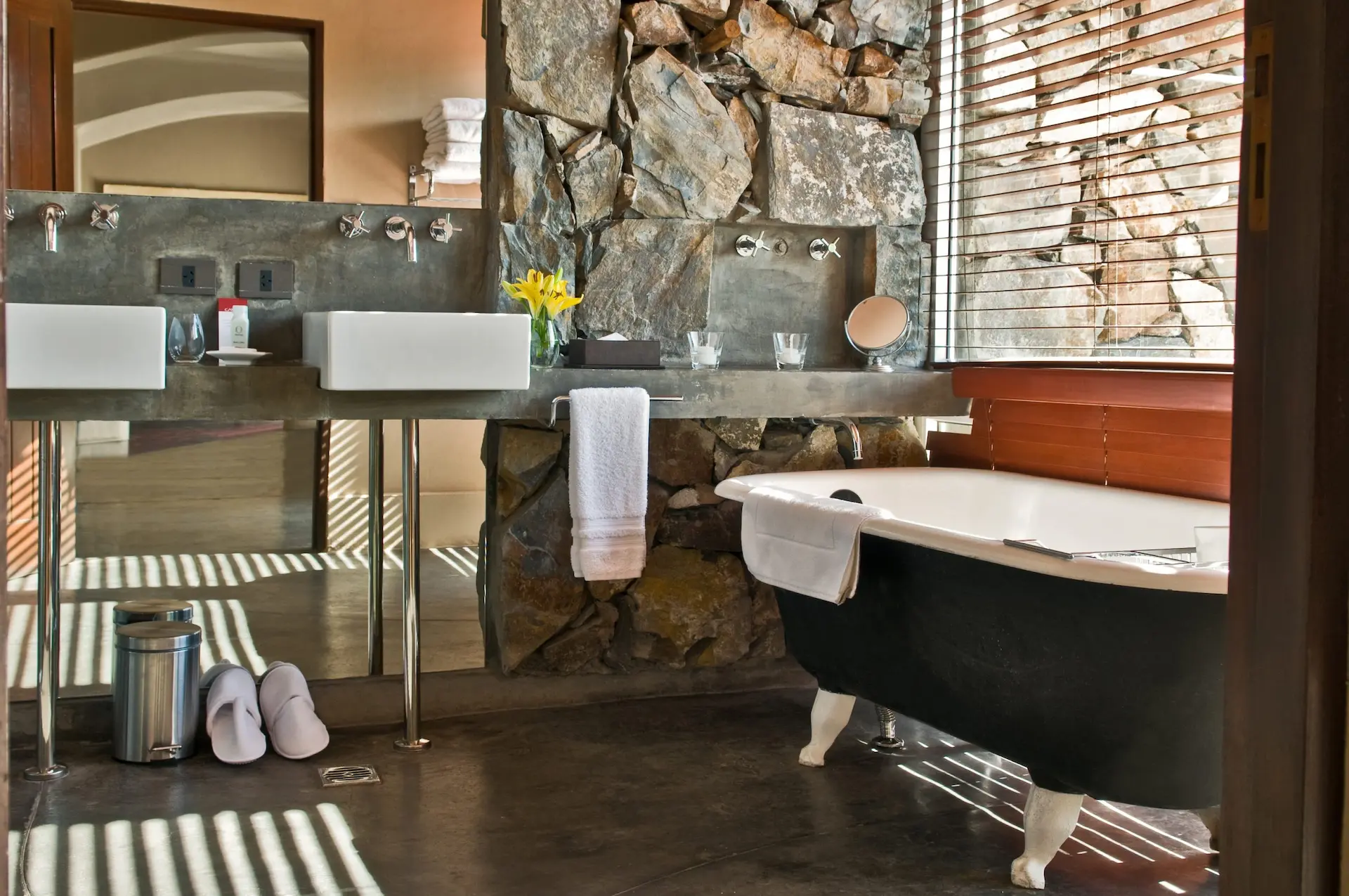 Luxury bathroom with freestanding bathtub stone wall double sinks and natural light creating a spa like atmospher