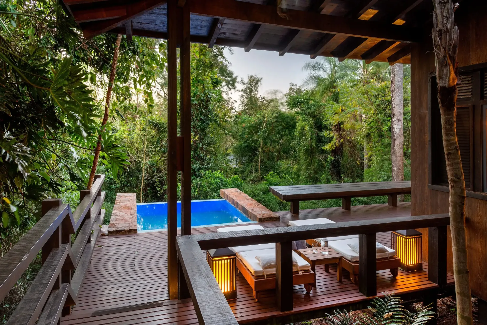 Luxury Jungle Lodge Deck With Lounge Chairs And A Private Pool Surrounded By Lush Tropical Greenery.