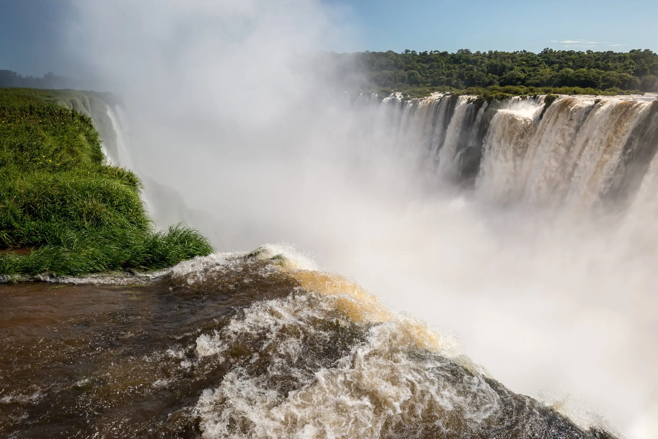 Powerful Waterfall Plunging Into A Mist-Filled Gorge Surrounded By Lush Green Cliffs.