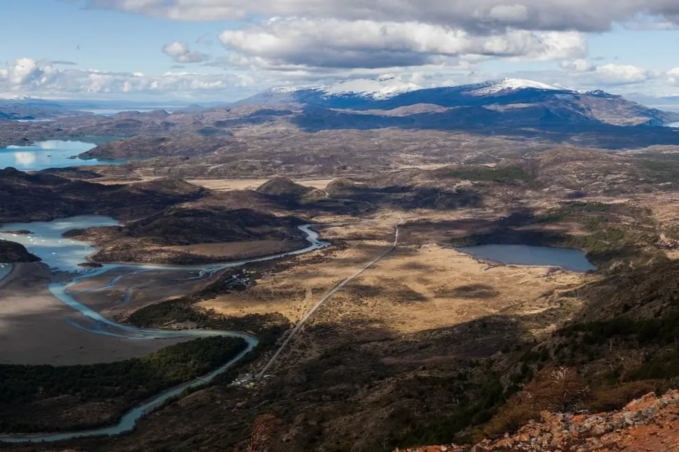 An Aerial Landscape Shows A Winding River And Valley Before Snow-Dusted Mountains.