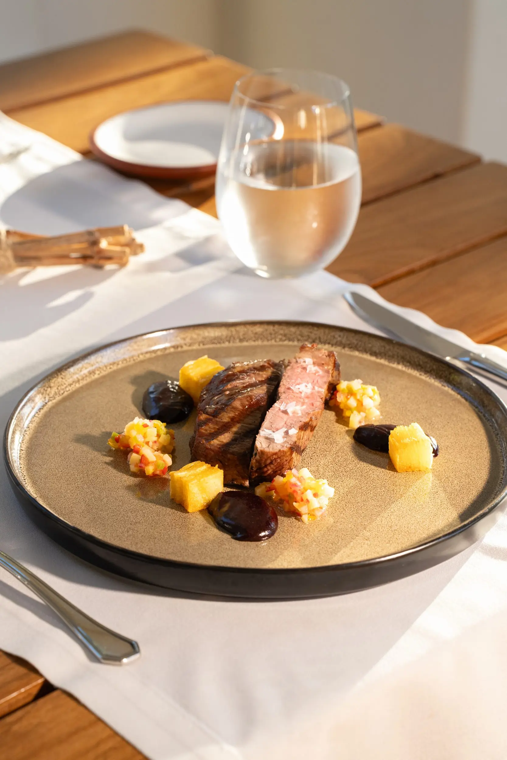 A Gourmet Steak Dish Is Served With Diced Fruit Salsa And Rich Dark Sauce On A Round Plate.