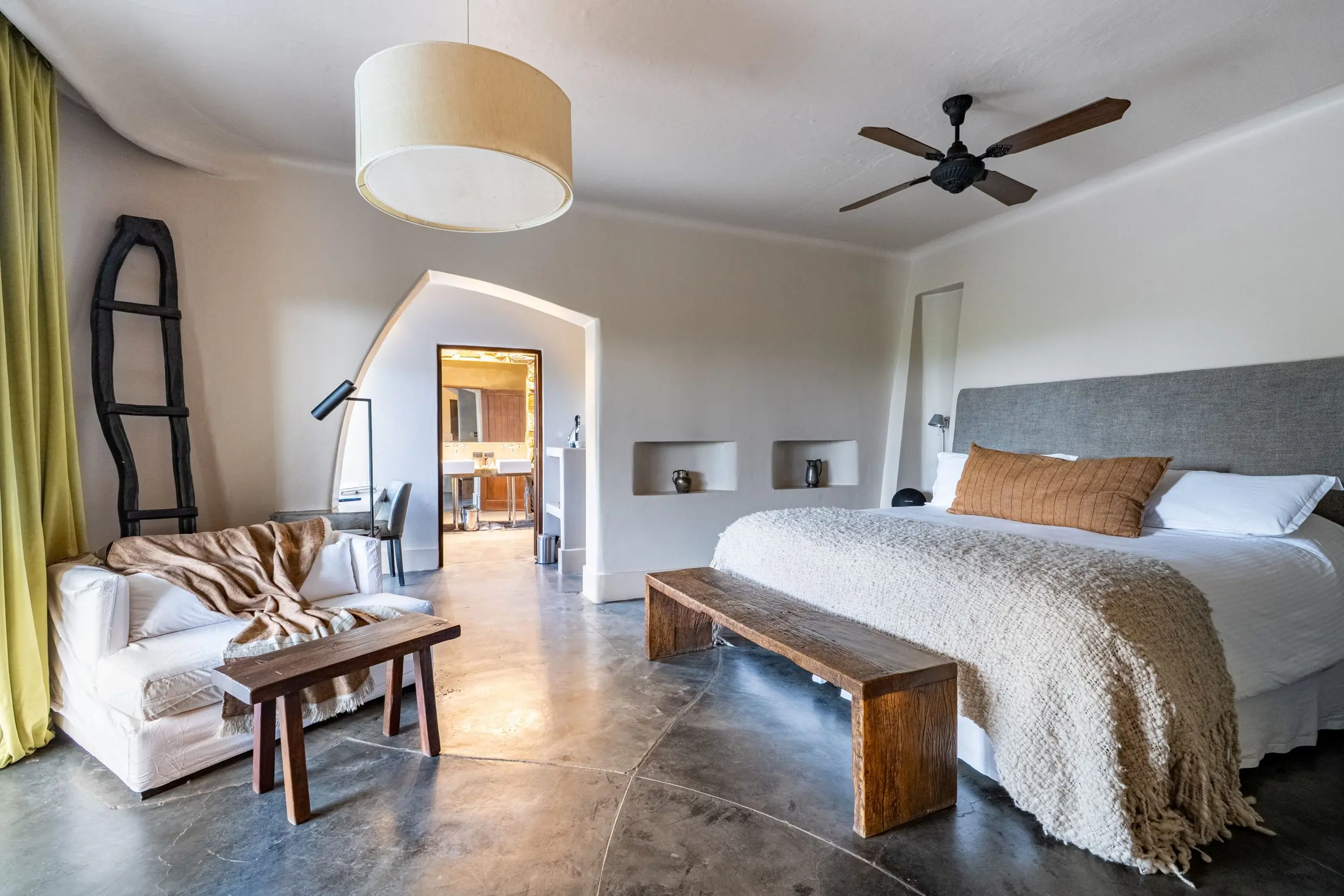 A Spacious, Minimalist Luxury Bedroom With Earthy Tones And An Attached Bathroom.