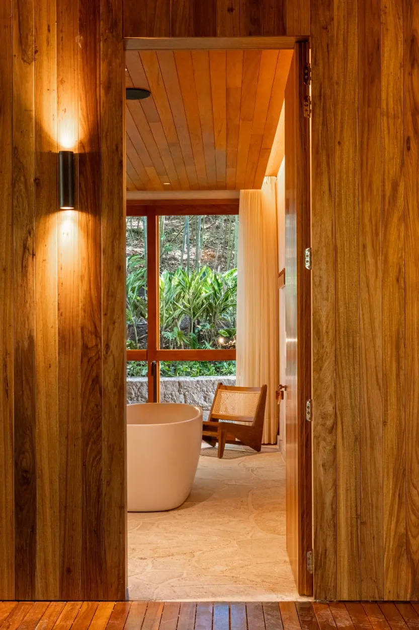 A Modern Wooden Doorway Opens Into A Luxury Bathroom With A Freestanding Tub.